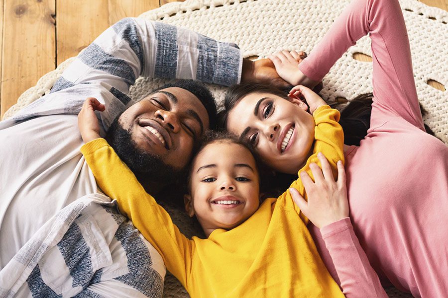Personal Insurance - Smiling Family Laying On Floor In Their Home